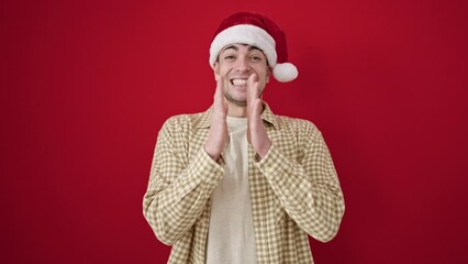 Wall Mural - Young hispanic man wearing christmas hat clapping hands applause over isolated red background