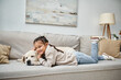 © LIGHTFIELD STUDIOS - happy girl smiling and lying on sofa with cute labrador in modern living room, pet and kid
