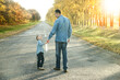 © Kostia - A Happy parent with child are walking along the road in the park on nature travel
