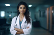 Portrait of a beautiful young female indian doctor in a hospital with her arms crossed in a white coat with stethoscope. Medical concept. Copy space
