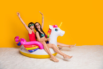 Poster - Photo of positive cheerful girls swim sand on rubber pony horse enjoy summer resort isolated bright color background