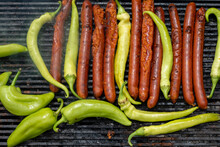 Green Peppers And Pork Sausages On The Barbecue Grill. Fresh Anaheim Chili Peppers Roasting Over A Charcoal Fire.  Cooking Peppers At The Barbecue.  Cayenne Pepper.