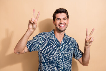 Sticker - Portrait of toothy beaming nice guy with trendy hairdo wear stylish shirt two hands show v-sign isolated on beige color background