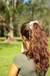 © Wirestock - Female with a brown hair and a bun in a park at a sunny day shot from behind