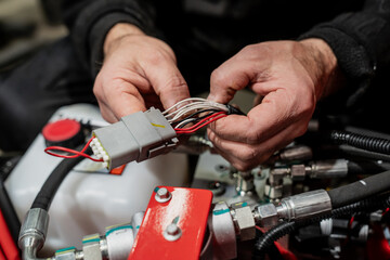 Electrician working on engine electric wiring close up with bare hands