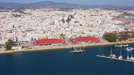 Canvas Print - Aerial drone footage of the Portuguese southern town of Olhao. View of the city and municipal market and old tourist sailboat.