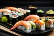 Appetizing sushi set from salmon makizushi and nigirizushi with various toppings served on a black plate with wasabi and soy sauce
