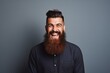Laughing young man wearing a long hipster beard looking at the camera.
