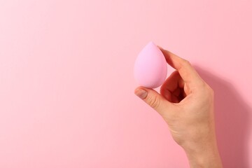 Woman with makeup sponge on pink background, top view. Space for text