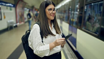 Sticker - Young beautiful hispanic woman waiting for the subway using smartphone in subway station of Madrid