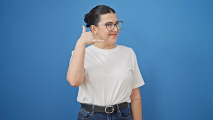 Poster - Young beautiful hispanic woman smiling confident doing telephone gesture with hand over isolated blue background