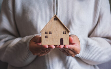 Wall Mural - Closeup image of a woman holding and showing a wooden house model