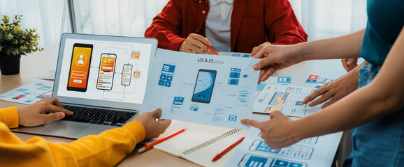 Panorama banner of startup UX developer or company employee design user interface or UI prototype for mobile application or website software with software display on laptop monitor in office. Synergic