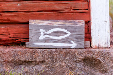 A wooden fish sign in front of a red painted board wall.