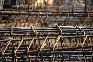 grey silver color steel rebar column reinforcement with stirrups. closeup abstract view. selective focus. blurred background. construction concept. building site. building industry.  