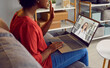© Studio Romantic - Shoulder view of African American woman talking to doctor online from home. Professional female doctor, general practitioner, medical specialist consulting young woman patient on webcam