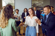 Partnership approval and teamwork. Female business colleagues congratulating each other on business achievements and excellent results at work. Women shake hands to applause of joyful business team.