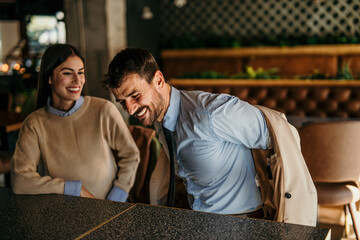 Wall Mural - Smiling business people relaxing just walk into a restaurant, take off their jackets, and sit at the table.