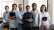 © fizkes - Multiethnic confident group of happy employees, office workers of different races holding notebooks, pads, looking at camera, smiling. Group portrait of Indian female business leader with team
