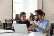 © fizkes - Happy multiethnic office colleagues employees talking at shared laptop, discussing online project presentation, collaborating on work tasks, startup ideas, solutions