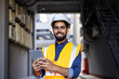 © Liubomir - Happy engineer builder in helmet standing near building with tablet in hands, arab work foreman looking and smiling at camera, senior project worker designer leader concept.