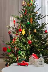 Wall Mural - Christmas holidays. Little houses, toys and christmas decorations on the table next to the Christmas tree.  Merry Christmas and Happy Holidays!