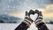 Hands in knitted mittens with heart of snow in a winter day