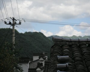 Roof of a house with blurred hills and electrical power lines on the background