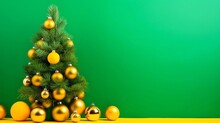 Christmas Tree With Golden Balls On Yellow Table And Green Background. Christmas And New Year Concept.