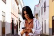 Young Hispanic Woman Using Her Mobile Phone In City. Mobile App Technology Concept