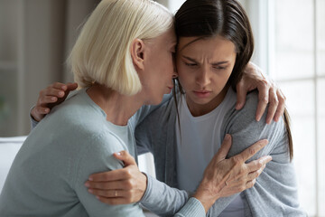 Caring mature mother comforting, hugging upset adult daughter close up, loving older grandmother soothing unhappy sad granddaughter, expressing empathy and support, helping overcome problems