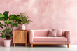 Pink upholstered sofa with cushings and side cabinet with potted floor plants set against a pink colour washed wall and grey floor modern interior room design