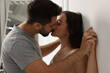 © New Africa - Passionate young couple kissing near white wall indoors
