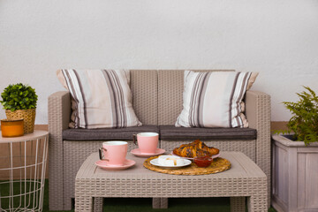 Canvas Print - Outdoor breakfast with tea and croissants on rattan table on terrace