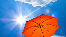 Umbrella In The Sun Against Blue Sky. Hot Summer Relaxation And Vacation Concept