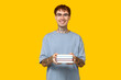 Young tattooed man with books on yellow background