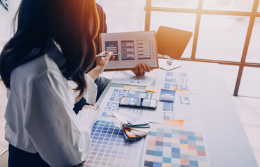 Close up ux developer and ui designer brainstorming about mobile app interface wireframe design on table with customer breif and color code at modern office.Creative digital development agency