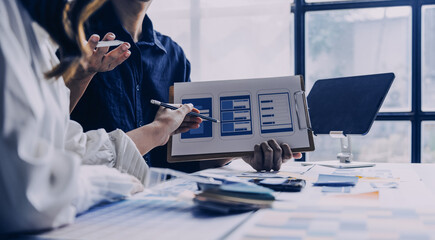 Close up ux developer and ui designer brainstorming about mobile app interface wireframe design on table with customer breif and color code at modern office.Creative digital development agency