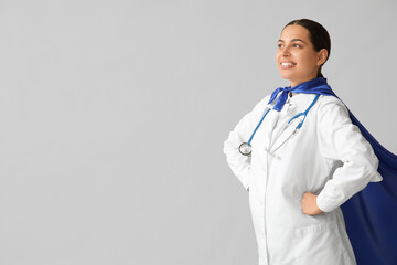 Beautiful female doctor in superhero costume on white background