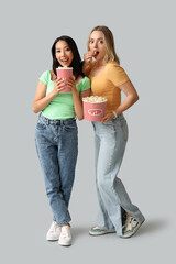 Wall Mural - Beautiful young women with buckets of popcorn on white background