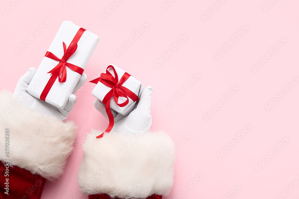 Santa Claus with white gift boxes on pink background