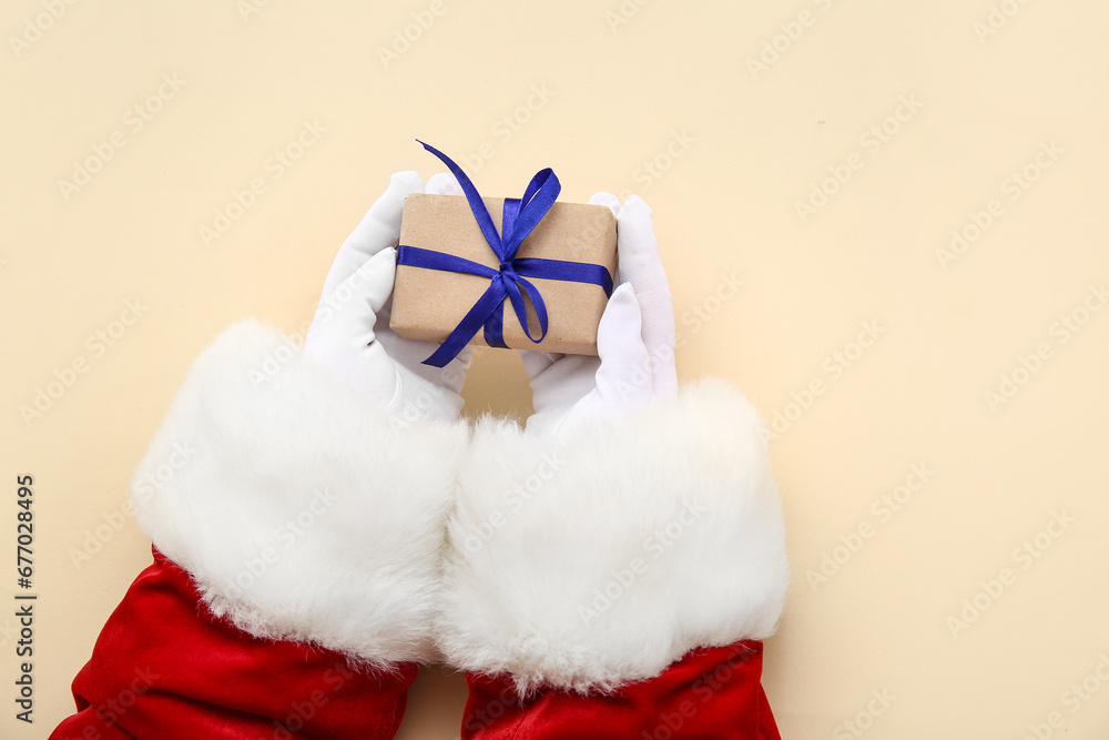 Santa Claus with gift box on beige background