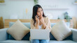 © Monster Ztudio - Young asian woman using computer laptop and mobile smartphone while seated on couch at home