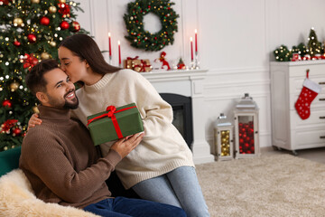 Wall Mural - Beautiful young couple with Christmas gift at home