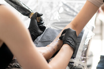 Wall Mural - a gorgeous tattoo of a flower on woman's hand, tattoo artist in the process of work