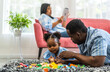 © Art_Photo - Portrait of happy love black family african american father and mother with little girl smiling activity learn and skill brain training play with toy build wooden blocks board education game at home