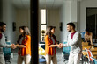 © BGStock72 - Young business couple standing and handshaking in front of her team at the office