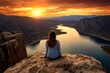© blvdone - Young woman sitting on a rock overlooking lake and canyong
