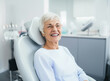 Portrait of a beautiful senior woman in elegant glasses with healthy smile sitting at the dental office. Joyful elderly lady in the clinic.