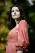 © Corina - Profile portrait of a beautiful brunette girl in dress posing in the green park, tree background.